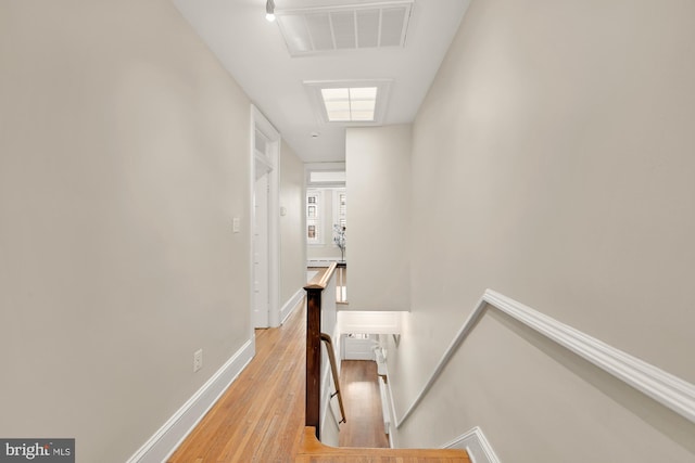 corridor with baseboards, an upstairs landing, visible vents, and light wood-type flooring