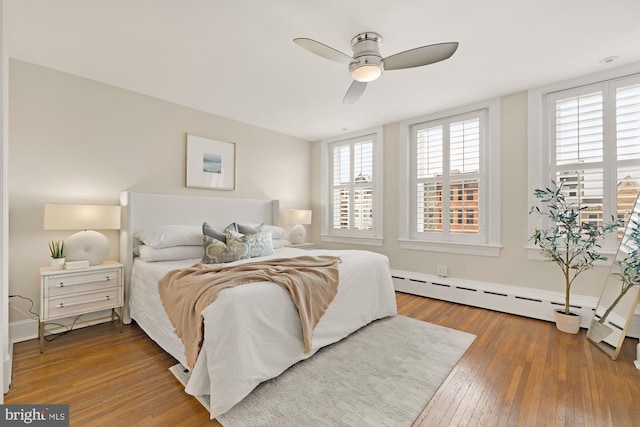 bedroom featuring a baseboard radiator, wood-type flooring, and ceiling fan