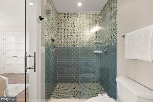 bathroom featuring a shower stall, toilet, and wood finished floors