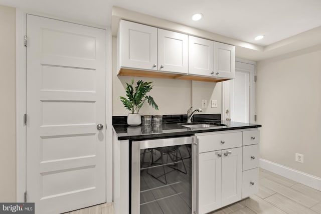 bar with baseboards, beverage cooler, indoor wet bar, recessed lighting, and a sink