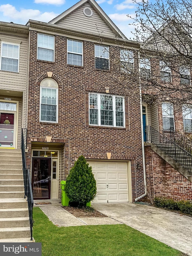 view of property with stairway, driveway, brick siding, and an attached garage