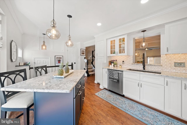 kitchen featuring a sink, dishwasher, a breakfast bar, and white cabinets