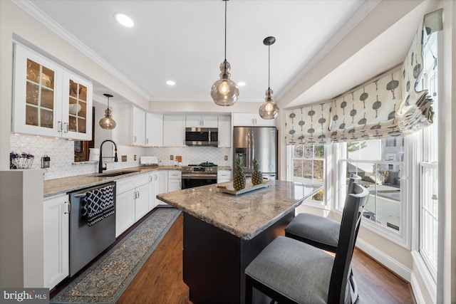 kitchen with crown molding, dark wood finished floors, light stone counters, appliances with stainless steel finishes, and a sink