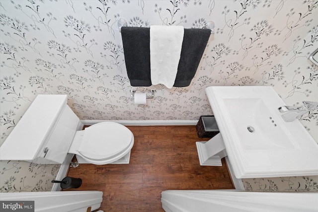 half bath featuring toilet, wallpapered walls, and baseboards