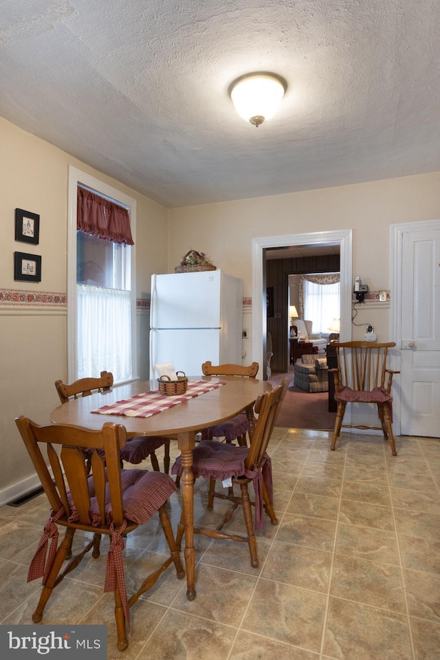 dining room with light tile patterned floors, visible vents, and a textured ceiling