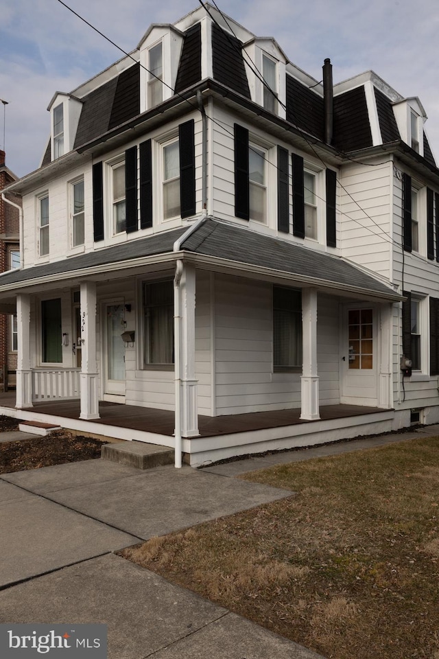 view of front facade featuring mansard roof, covered porch, and a shingled roof