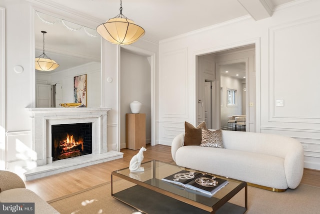 living area featuring a decorative wall, a fireplace, crown molding, and wood finished floors