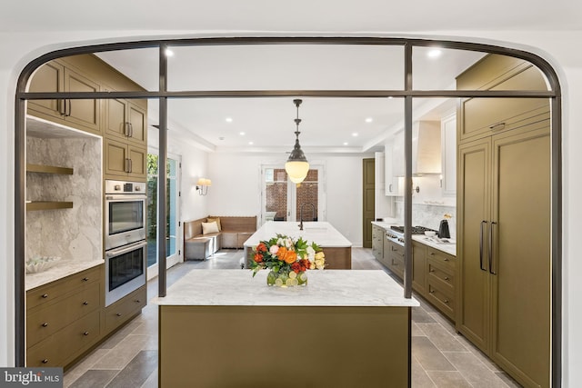 kitchen featuring recessed lighting, stainless steel double oven, a center island with sink, and decorative backsplash