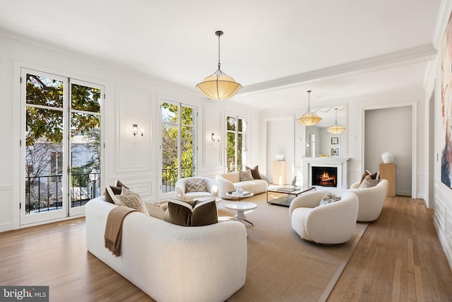 living area with wood finished floors, ornamental molding, and a decorative wall