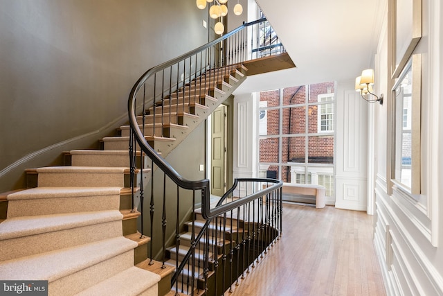 stairway featuring a chandelier, a decorative wall, and wood finished floors