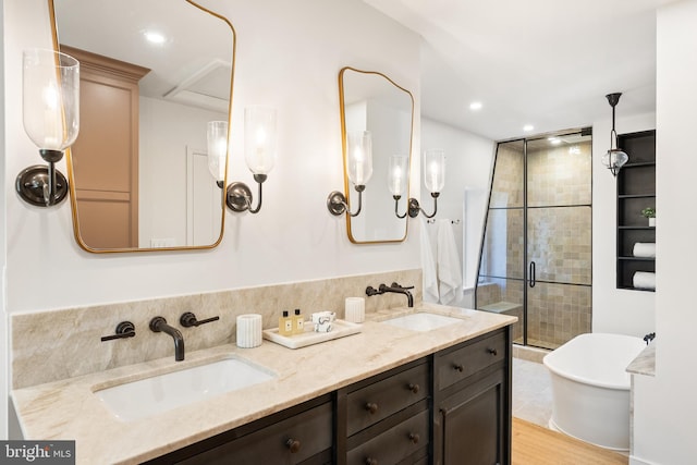 bathroom with a freestanding bath, double vanity, a stall shower, and a sink