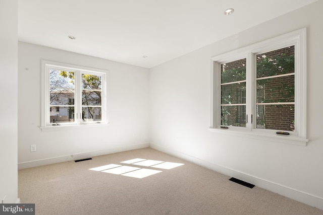 carpeted empty room featuring visible vents and baseboards