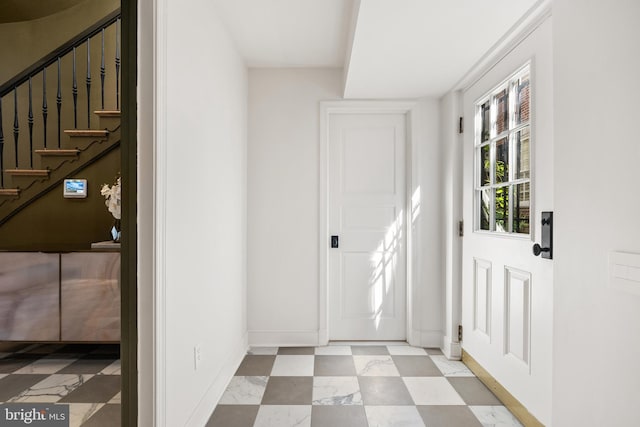 doorway featuring baseboards, light floors, and stairs