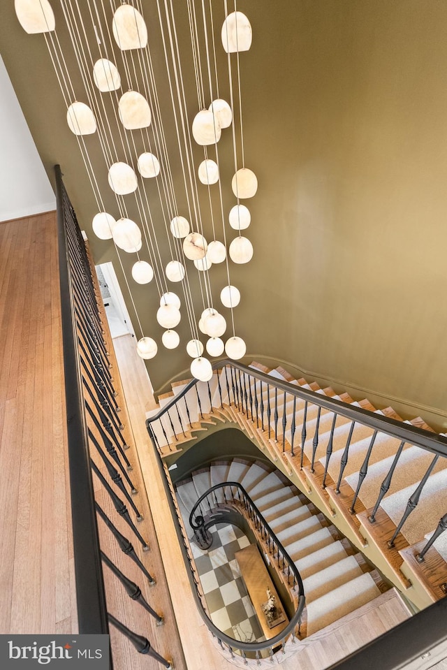 stairs featuring wood-type flooring and a chandelier