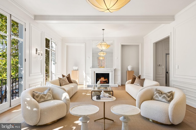 living room featuring crown molding, a decorative wall, light wood-type flooring, and a warm lit fireplace