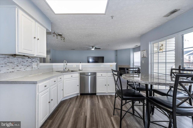 kitchen featuring a sink, stainless steel dishwasher, dark wood finished floors, a peninsula, and ceiling fan