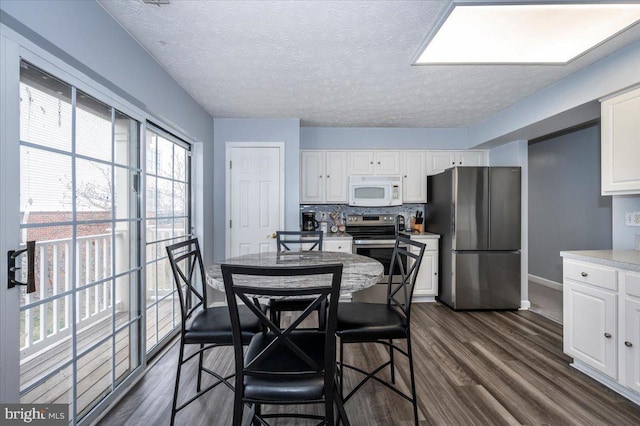 dining room featuring dark wood-style floors, a textured ceiling, and baseboards