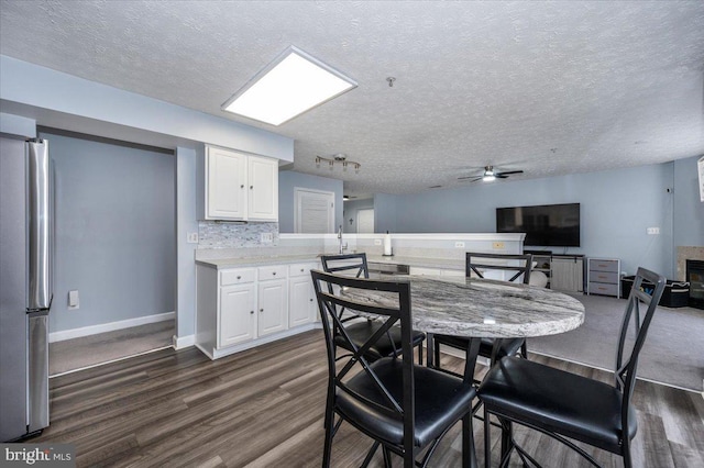 dining space featuring a textured ceiling, baseboards, dark wood-type flooring, and ceiling fan