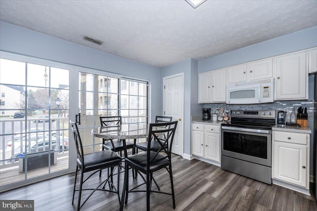 kitchen featuring visible vents, dark wood-type flooring, stainless steel electric stove, white cabinetry, and white microwave