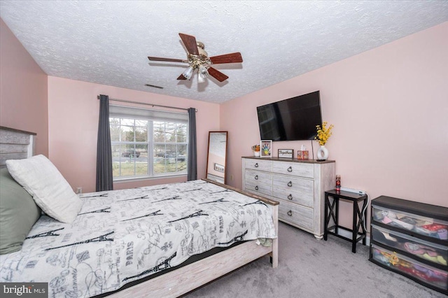 carpeted bedroom featuring a ceiling fan and a textured ceiling