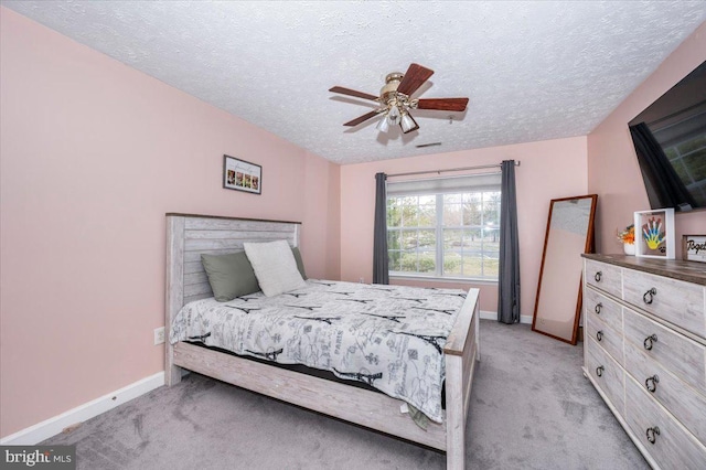 bedroom featuring light colored carpet, baseboards, and a textured ceiling