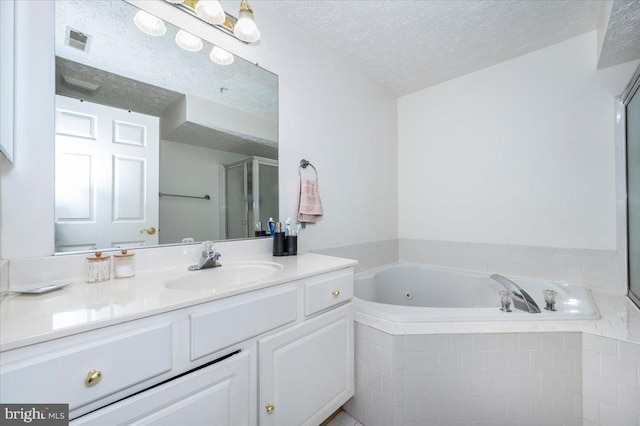 full bathroom with visible vents, a stall shower, a textured ceiling, a jetted tub, and vanity