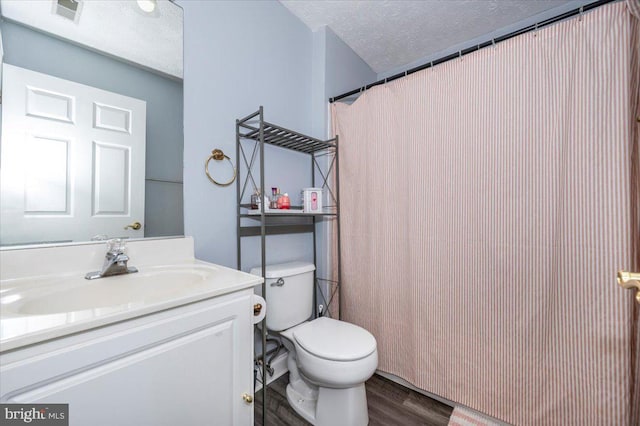 bathroom featuring vanity, wood finished floors, visible vents, a textured ceiling, and toilet