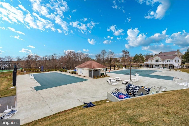 view of swimming pool featuring a patio area, a yard, and fence