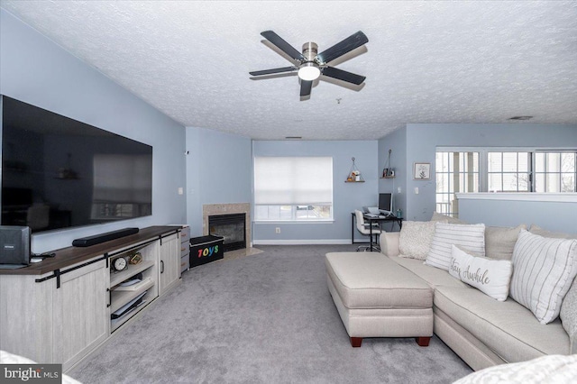 living room featuring a textured ceiling, a fireplace with flush hearth, a ceiling fan, and light carpet