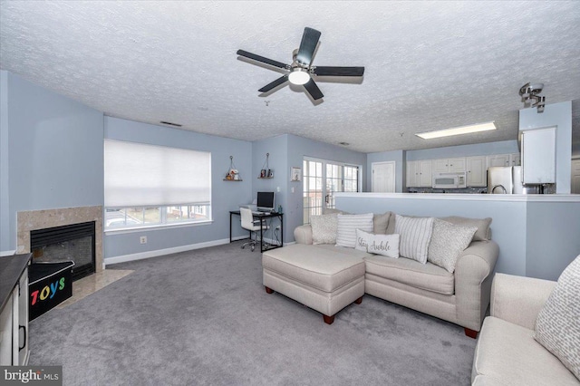 carpeted living area with baseboards, a ceiling fan, a fireplace, and a textured ceiling