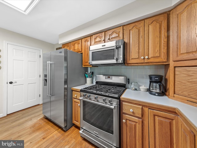 2446 Saint Lukes Rd, Salisbury, MD 21804 - kitchen with appliances with stainless steel finishes, light countertops, brown cabinetry, tasteful backsplash, and light wood-type flooring