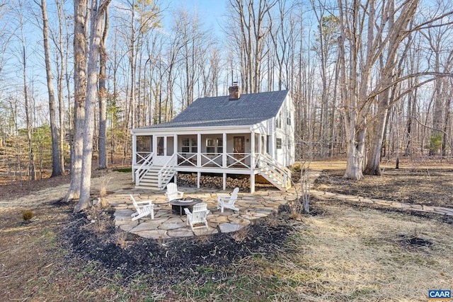 view of front of house featuring a chimney, an outdoor fire pit, stairs, and a shingled roof