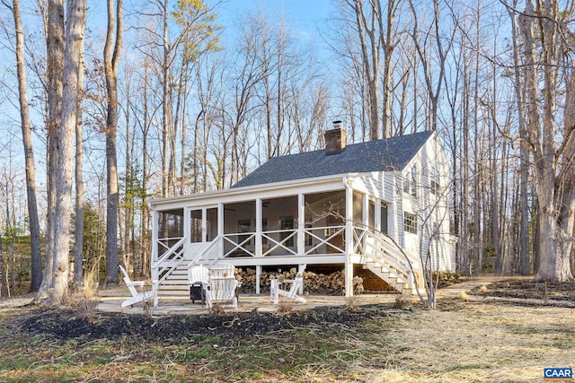 view of front of home with stairway, roof with shingles, a chimney, and a sunroom