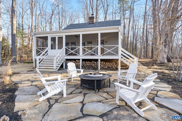 view of patio / terrace with an outdoor fire pit, stairs, ceiling fan, and a sunroom