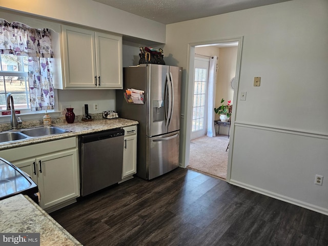 kitchen featuring baseboards, appliances with stainless steel finishes, dark wood-style floors, a textured ceiling, and a sink