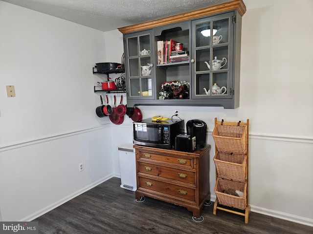 bar featuring dark wood-style floors, baseboards, black microwave, and a textured ceiling