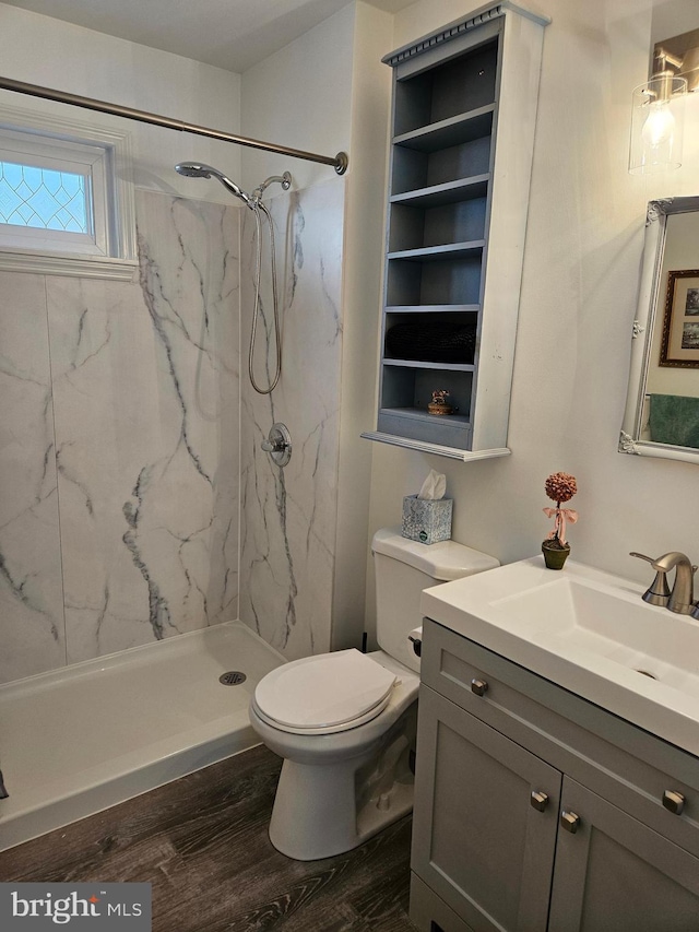 full bath with a marble finish shower, toilet, vanity, and wood finished floors