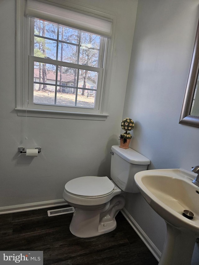 bathroom featuring wood finished floors, toilet, visible vents, and plenty of natural light