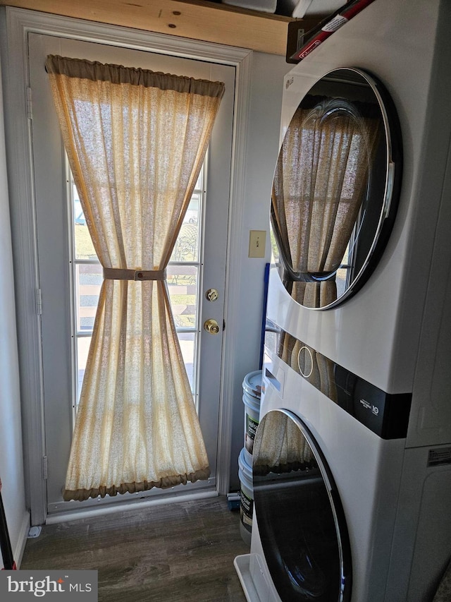 washroom with wood finished floors, laundry area, and stacked washer / dryer