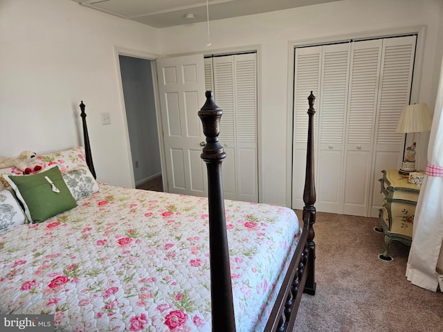 bedroom with attic access, carpet flooring, and two closets