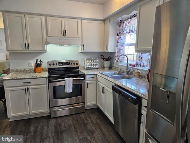 kitchen with under cabinet range hood, dark wood finished floors, white cabinets, stainless steel appliances, and a sink