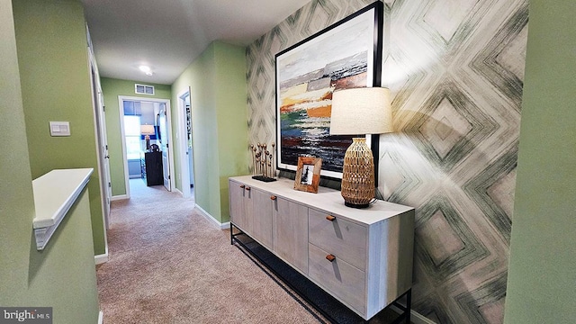 hallway with carpet flooring, baseboards, and visible vents