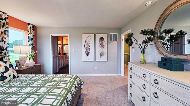 bedroom featuring ensuite bathroom, baseboards, visible vents, and dark colored carpet