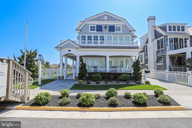 1 103rd St, Stone Harbor, NJ 08247 - view of front facade with driveway, a gate, fence, covered porch, and a balcony