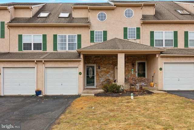 multi unit property featuring stone siding, stucco siding, driveway, and roof with shingles