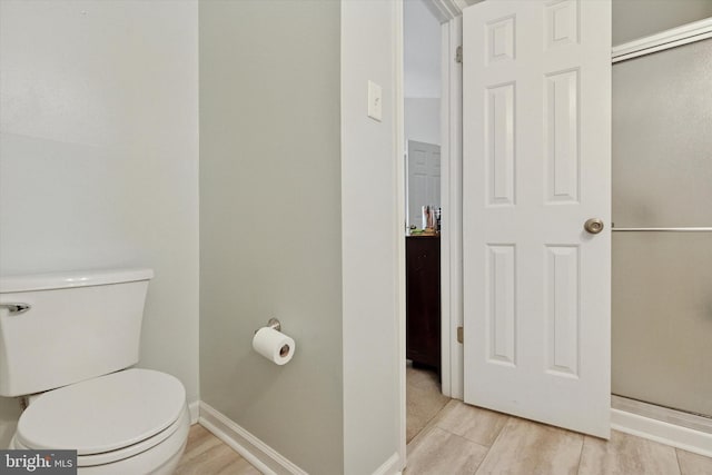 bathroom with baseboards, toilet, and wood finished floors