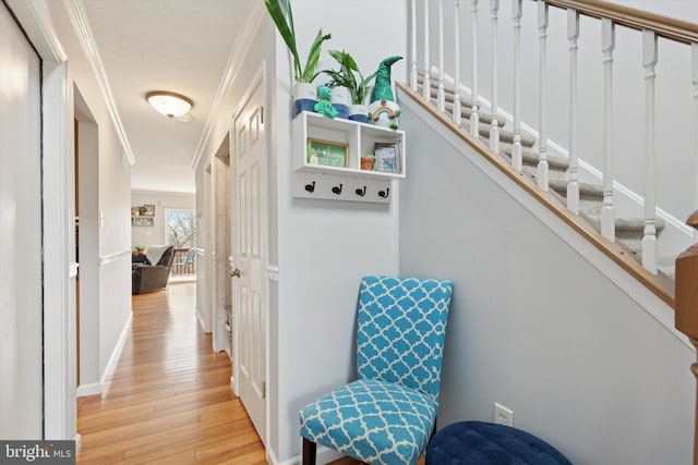 hall with light wood finished floors, stairway, crown molding, and baseboards