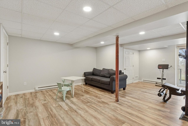 exercise room with baseboard heating, baseboards, and light wood-style floors