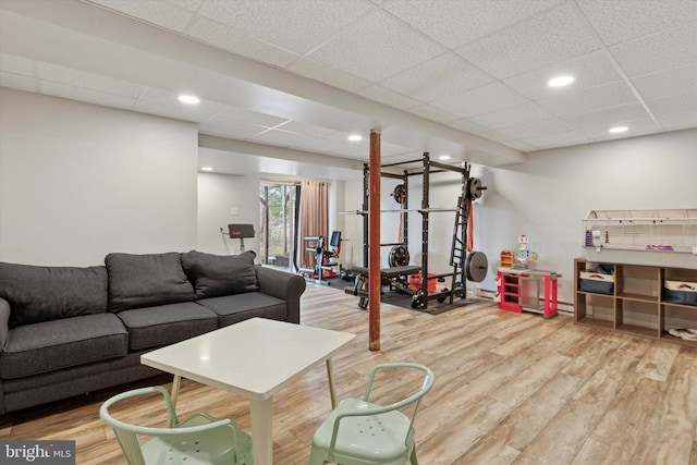 living area with recessed lighting, a paneled ceiling, and wood finished floors