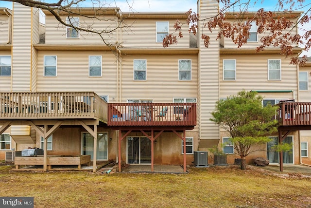 back of property with a deck, central AC unit, and a yard